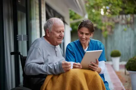 healthcare professional showing elderly man an electronic tablet