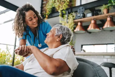 happy elder talking with caregiver at home
